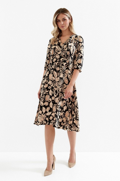 Na modelce sukienka w kolorze czarnym w brązowy roślinny wzór, o długości midi, lekko rozkloszowana, z odcięciem pod biustem w kształcie trójkąta, z lekkim przymarszczeniem, dekolt w literkę v, rękaw o długości 7/8 zakończony gumką.