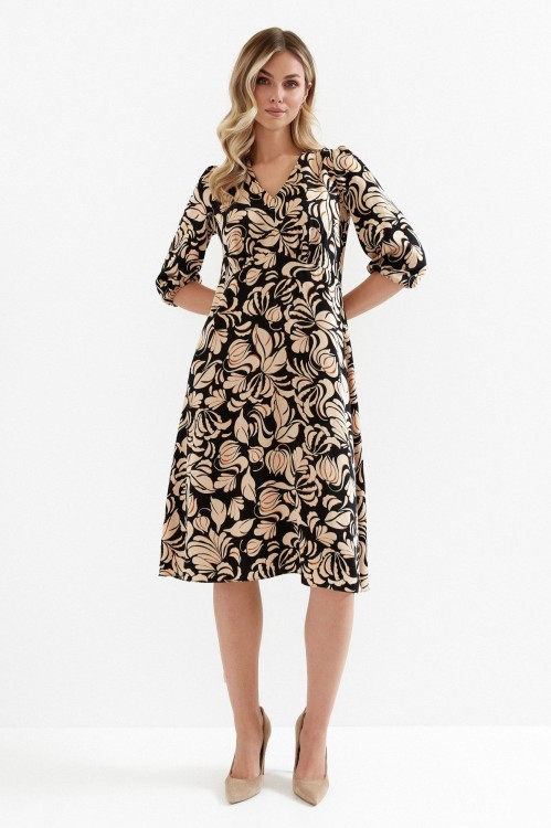 Na modelce sukienka w kolorze czarnym w brązowy roślinny wzór, o długości midi, lekko rozkloszowana, z odcięciem pod biustem w kształcie trójkąta, z lekkim przymarszczeniem, dekolt w literkę v, rękaw o długości 7/8 zakończony gumką.