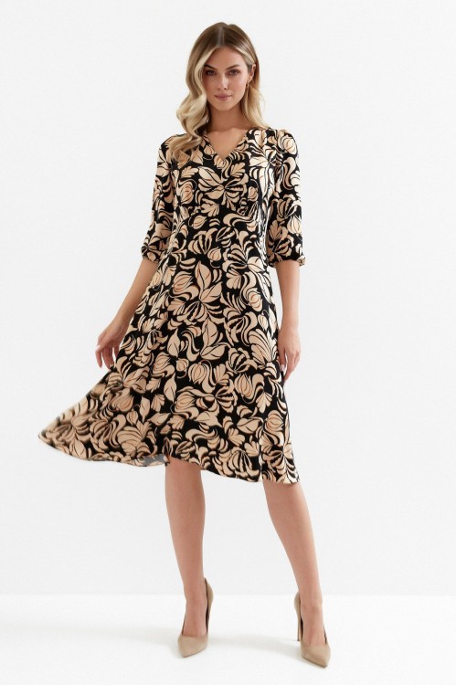 Na modelce sukienka w kolorze czarnym w brązowy roślinny wzór, o długości midi, lekko rozkloszowana, z odcięciem pod biustem w kształcie trójkąta, z lekkim przymarszczeniem, dekolt w literkę v, rękaw o długości 7/8 zakończony gumką.