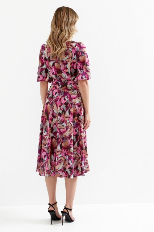 Na modelce stojącej tyłem sukienka rozkloszowana, kolorowa w odcieniach bordo, różu, brązu o długości midi, wiązana w talii, rękaw do łokcia zakończony gumką, zapinana na kryty suwak