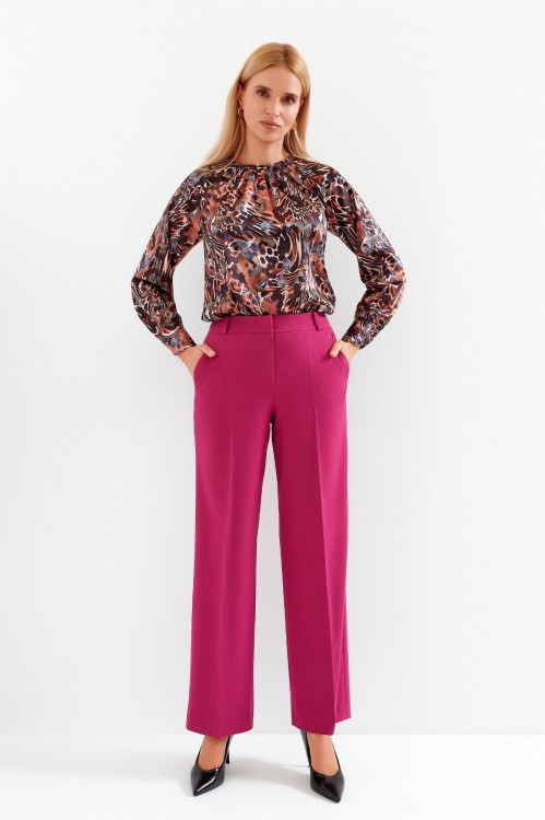 Na modelce szerokie spodnie w kant, w kolorze fuksjowym, z kieszeniami, zapinane na kryty suwak i haftkę, spodnie mają wszyty pasek ze szlufkami