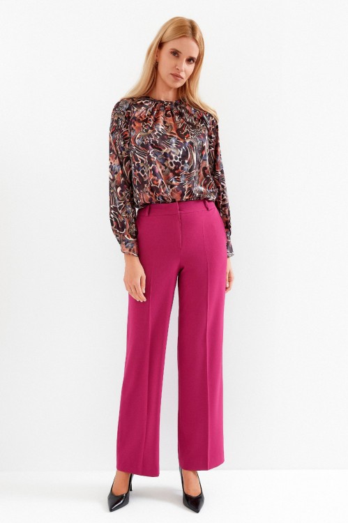 Na modelce szerokie spodnie w kant, w kolorze fuksjowym, z kieszeniami, zapinane na kryty suwak i haftkę, spodnie mają wszyty pasek ze szlufkami