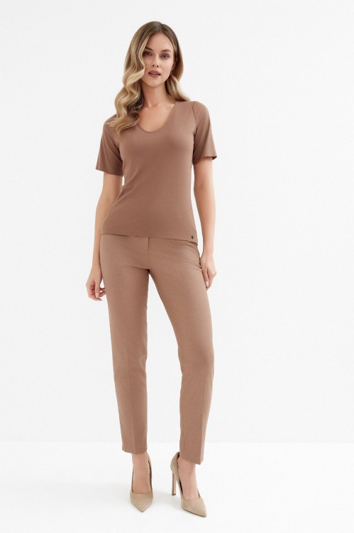 Na modelce top z krótkim rękawem, w kolorze jasnego brązu z dekoltem w serek.