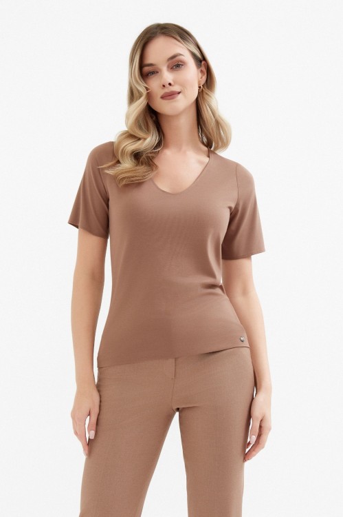 Na modelce top z krótkim rękawem, w kolorze jasnego brązu z dekoltem w serek.