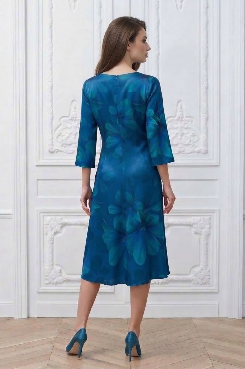 Na modelce stojącej tyłem sukienka niebieska w kwiaty, o długości midi, lekko rozkloszowana, zapinana na kryty suwak