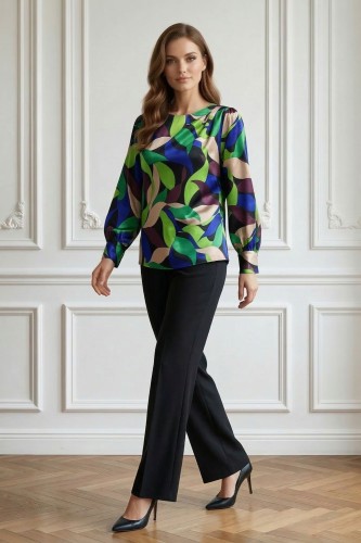 Na modelce stojącej przodem, elegancka, kolorowa bluzka z długim rękawem z mankietami; niewielkim, okrągłym dekoltem; ozdobnymi zakładkami na lewym ramieniu