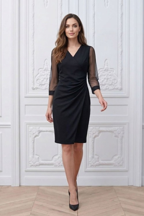 Na modelce stojącej przodem czarna kopertowa sukienka, o długości za kolano, szyfonowymi rękawami 7/8 z delikatną bufką na ramieniu i odszytym mankietem