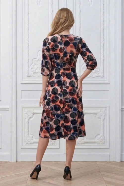Na modelce stojącej tyłem, sukienka w różnokolorowy wzór, o długości za kolana, lekko rozkloszowana, zapinana na kryty suwak