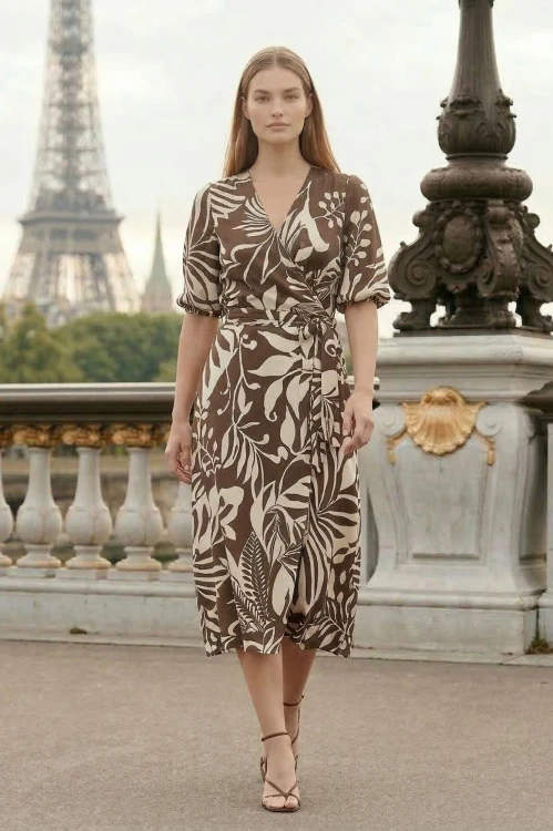 Na modelce elegancka sukienka z wiskozy z kopertowym dekoltem, sukienka w kolorze brązowym w ecru roślinny motyw, talia podkreślona paskiem, dół sukienki rozkloszowany, długość midi