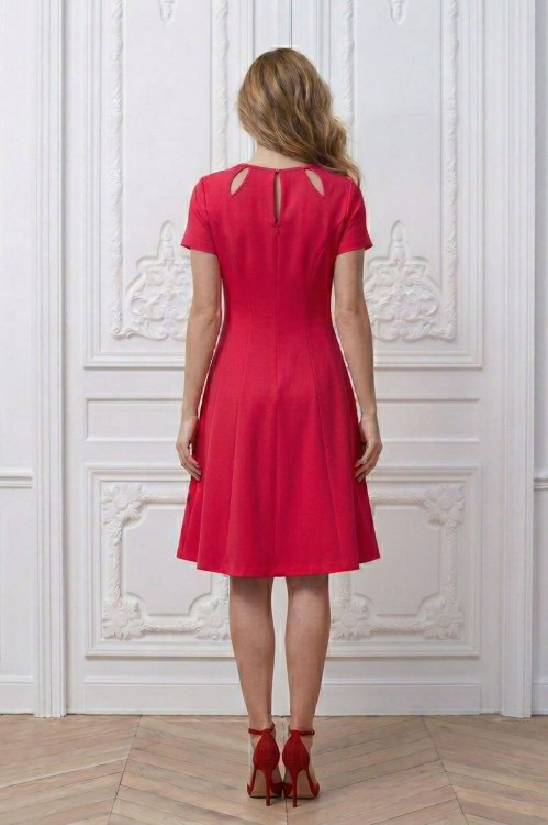 Na modelce stojącej tyłem, rozkloszowana sukienka w kolorze amarantowym z krótkimi rękawami,  Zapinana z tyłu na kryty suwak oraz ozdobną haftkę.