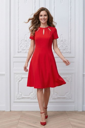 Na modelce rozkloszowana sukienka w kolorze czerwonym,  z krótkimi rękawami, okrągły dekolt, pod nim wycięto trzy ozdobne łezki.