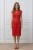 Na modelce stojącej przodem czerwona sukienka z koronki, o długości za kolana, transparentny koronkowy karczek z łódkowym dekoltem podkreśla linię ramion. Poniżej odcięcia w talii z przodu  znajdują się cztery zaszewki