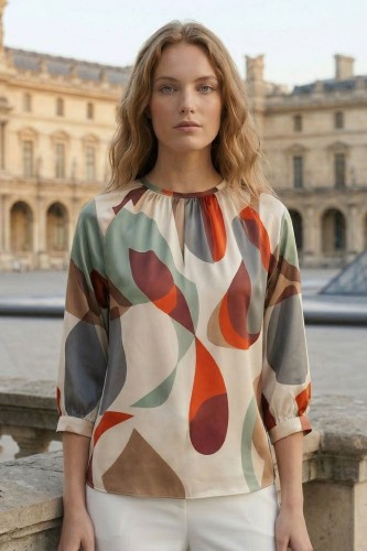 Na modelce stojącej przodem, bluzka o prostym fasonie w kolorowy wzór ecru, miętowy, pomarańczowy , z rękawami 3/4 z mankietami ,niewielkim, okrągłym dekoltem z rozcięciem