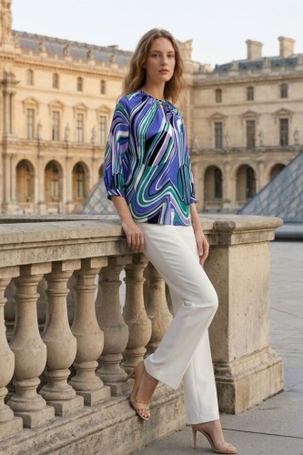 Na modelce stojącej bokiem, bluzka o prostym fasonie w kolorowy abstrakcyjny wzór, niebiesko, zielono, fioletowy , z rękawami 3/4 z mankietami , niewielkim, okrągłym dekoltem z rozcięciem