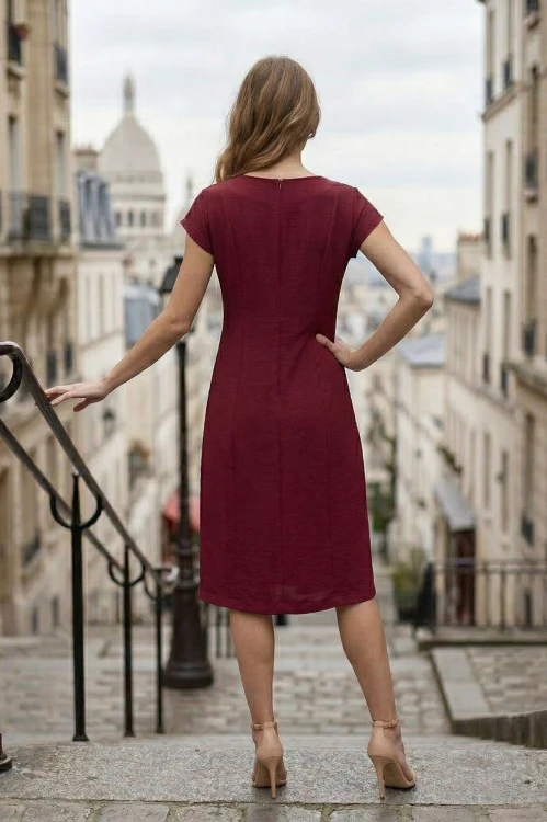 Na modelce stojącej tyłem bordowa sukienka z krótkim, kimonowy rękawem, lekko dopasowana do sylwetki zaszewkami modelującymi, zapinana na kryty suwak