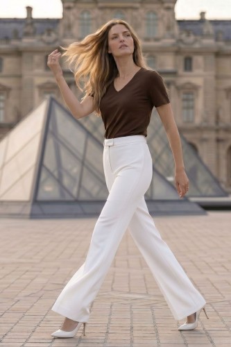 Na modelce szerokie spodnie w kant, w kolorze białym, zapinane na kryty suwak i haftkę, spodnie mają wszyty pasek ze szlufkami