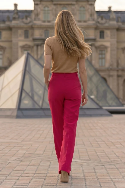 Na modelce stojącej tyłem szerokie spodnie w kant, w kolorze malinowym, spodnie mają wszyty pasek ze szlufkami