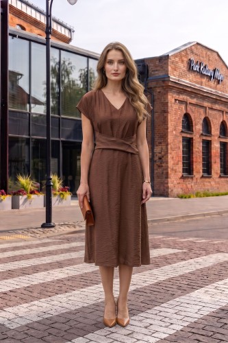 Na modelce midi sukienka w kolorze mlecznej czekolady, dekolt w delikatny serek, rękaw krótki reglanowy, w pasie materiałowa ozdoba, dół sukienki lekko rozkloszowany
