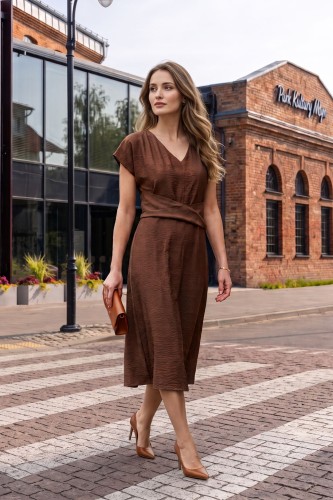 Na modelce midi sukienka w kolorze mlecznej czekolady, dekolt w delikatny serek, rękaw krótki reglanowy, w pasie materiałowa ozdoba, dół sukienki lekko rozkloszowany