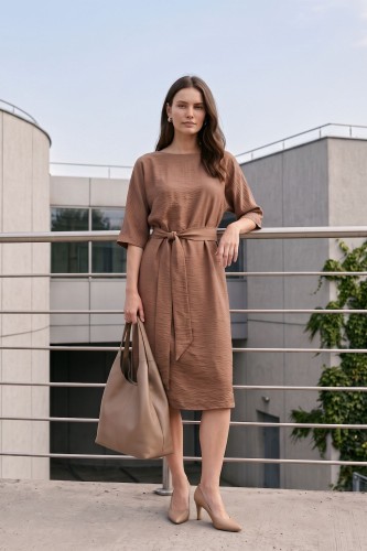 Na modelce stojącej przodem, sukienka w kolorze mlecznej czekolady, talia podkreślona paskiem, niewielki okrągły dekolt, rękawek kimonowy o długości za łokieć, dół sukienki za kolana lekko rozkloszowany