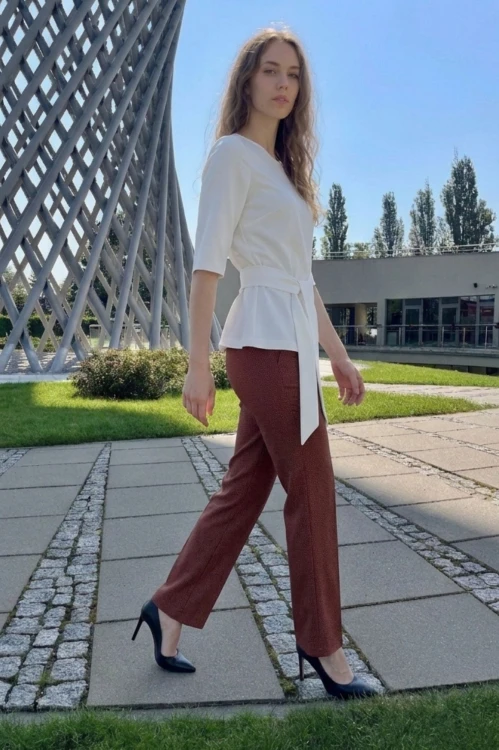 Na modelce biała bluzka z paskiem materiałowym, w tym samym kolorze co bluzka, z rękawami o długości 3/4, i niewielkim okrągłym dekoltem