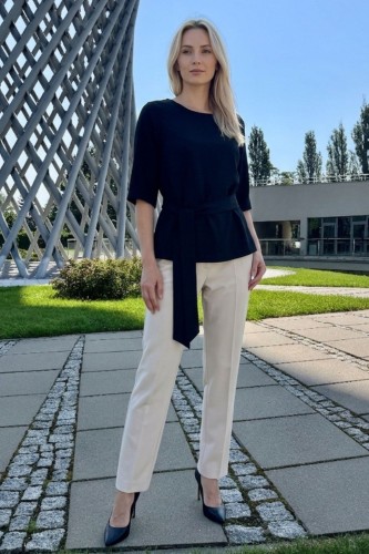 Na modelce czarna bluzka z paskiem materiałowym, w tym samym kolorze co bluzka, z rękawami o długości 3/4, i niewielkim okrągłym dekoltem
