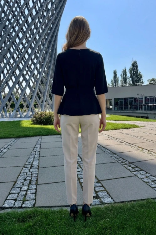 Na modelce stojącej tyłem czarna bluzka z paskiem materiałowym, w tym samym kolorze co bluzka, z rękawami o długości 3/4, i niewielkim okrągłym dekoltem, na karku kryte pęknięcie zapinane na guzik