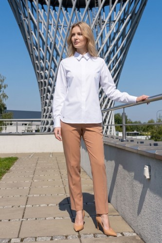 Na modelce elegancka biała koszula damska, o prostym kroju, z klasycznym kołnierzykiem, zapinana na guziki ukryte pod pionową listwą. Koszula ma długie rękawy zakończone mankietami zapinanymi na dwa guziki.