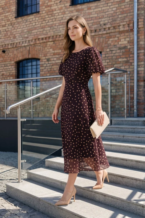 Na modelce elegancka sukienka w odcieniu burgundu w beżowe grochy, okrągły dekoltem, odcięciem po wyżej talii, krótkim, bufiastym rękawkiem zakończonym gumką, sukienka ma długość midi