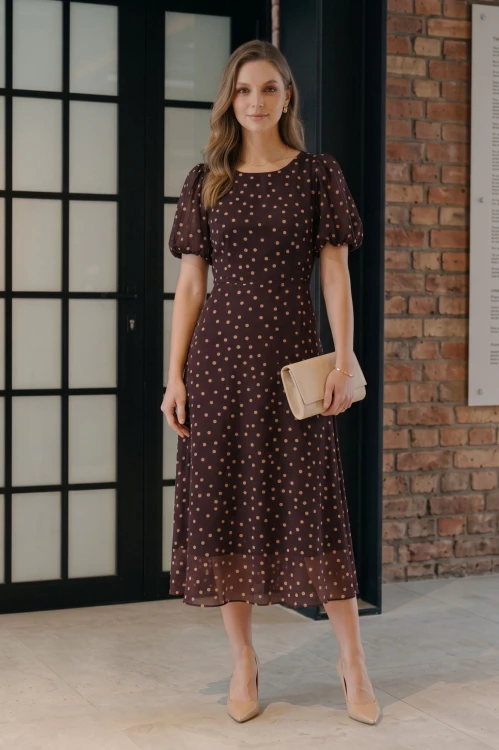 Na modelce elegancka sukienka w odcieniu burgundu w beżowe grochy, okrągły dekoltem, odcięciem po wyżej talii, krótkim, bufiastym rękawkiem zakończonym gumką, sukienka ma długość midi