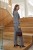 Na modelce stojącej bokiem garnitur z wyłogami, w kolorze jasnej szarości, zapinany na jeden guzik, oraz szerokie spodnie na kant